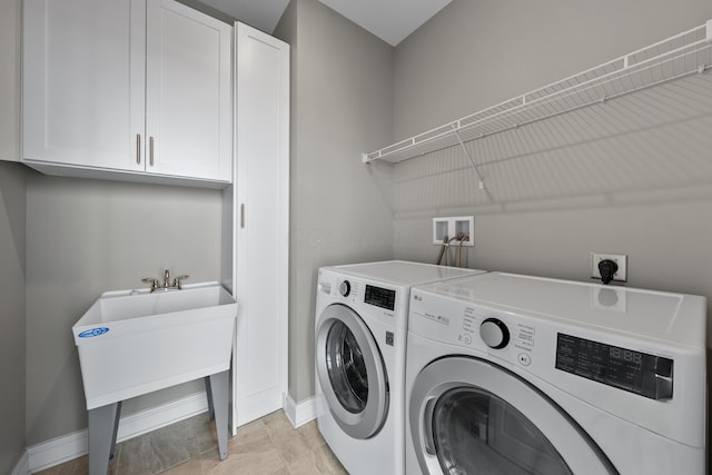 laundry room featuring washer and clothes dryer, a sink, cabinet space, and baseboards