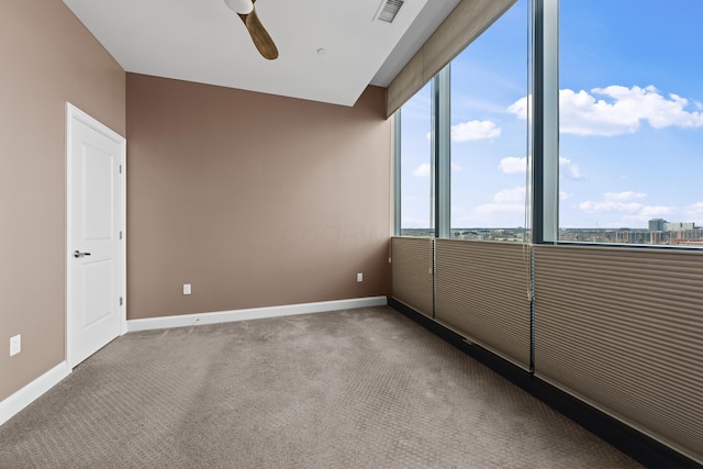 spare room with carpet floors, visible vents, baseboards, and a ceiling fan