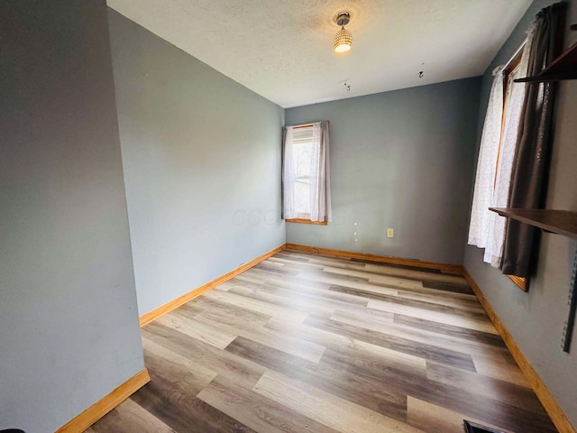 unfurnished room with light hardwood / wood-style floors and a textured ceiling