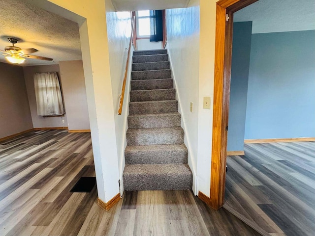 staircase featuring a textured ceiling, hardwood / wood-style flooring, and ceiling fan