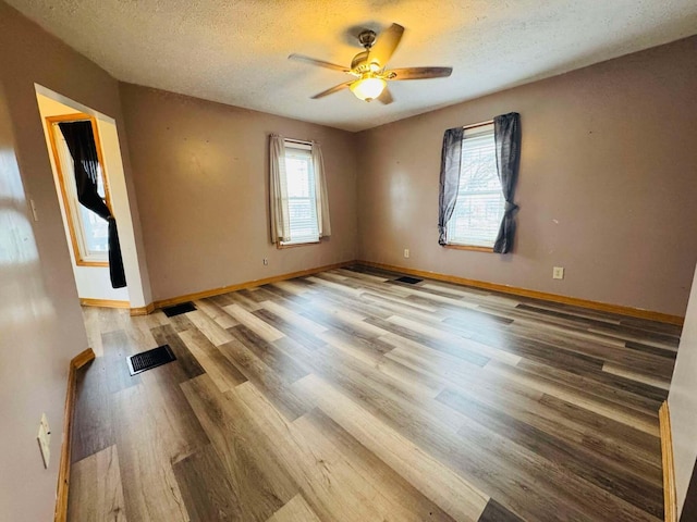 empty room featuring ceiling fan, wood-type flooring, and a textured ceiling