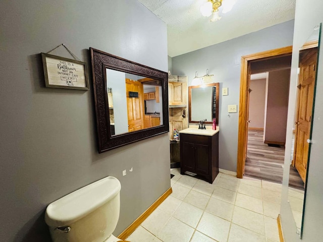 bathroom with tile patterned flooring, a textured ceiling, vanity, and toilet