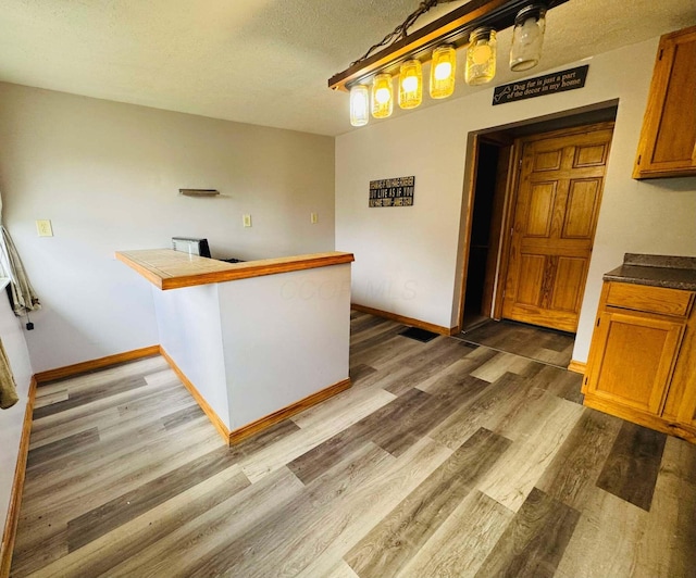 kitchen featuring kitchen peninsula, dark hardwood / wood-style flooring, hanging light fixtures, and a textured ceiling