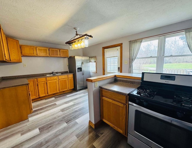 kitchen featuring sink, light hardwood / wood-style floors, a textured ceiling, and appliances with stainless steel finishes