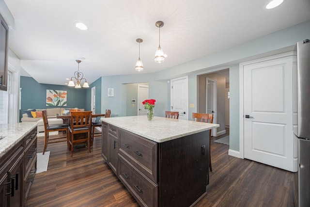 kitchen featuring a center island, an inviting chandelier, hanging light fixtures, and dark wood-type flooring