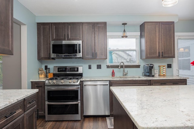 kitchen featuring pendant lighting, sink, dark hardwood / wood-style floors, appliances with stainless steel finishes, and dark brown cabinets