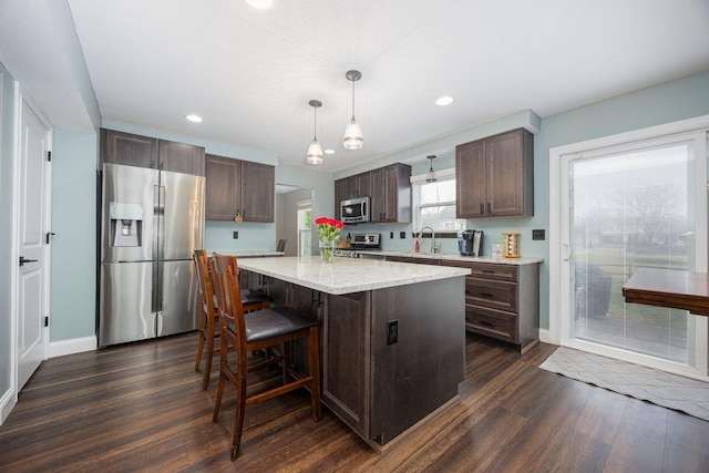 kitchen with pendant lighting, a center island, sink, dark hardwood / wood-style floors, and appliances with stainless steel finishes