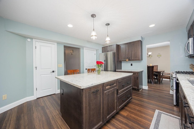 kitchen featuring appliances with stainless steel finishes, dark brown cabinets, a kitchen island, and hanging light fixtures