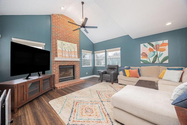 living room with vaulted ceiling, a brick fireplace, ceiling fan, and dark wood-type flooring