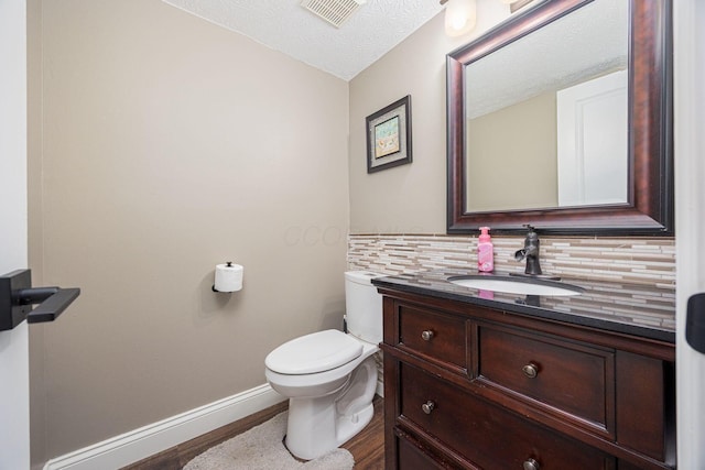 bathroom featuring vanity, a textured ceiling, toilet, and backsplash