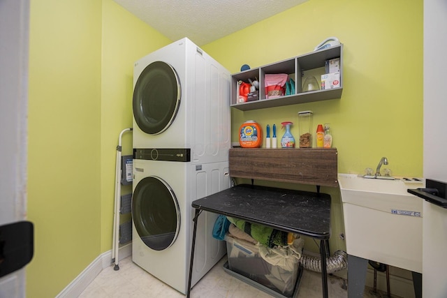 washroom featuring a textured ceiling, sink, and stacked washer / drying machine