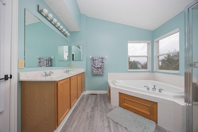 bathroom with tiled bath, vanity, lofted ceiling, and hardwood / wood-style flooring