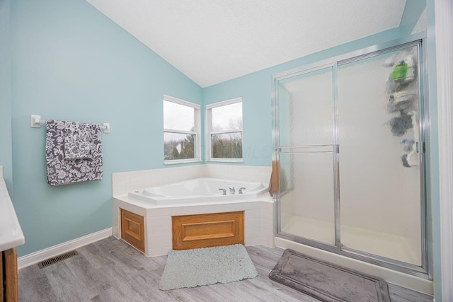 bathroom with hardwood / wood-style floors, separate shower and tub, a textured ceiling, and vaulted ceiling