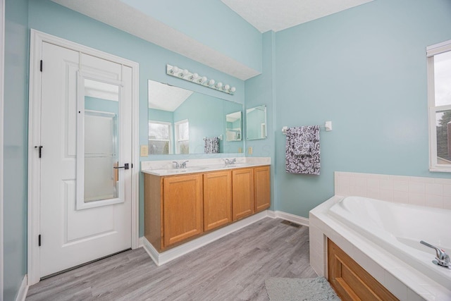 bathroom featuring a bath, vanity, hardwood / wood-style flooring, and a textured ceiling