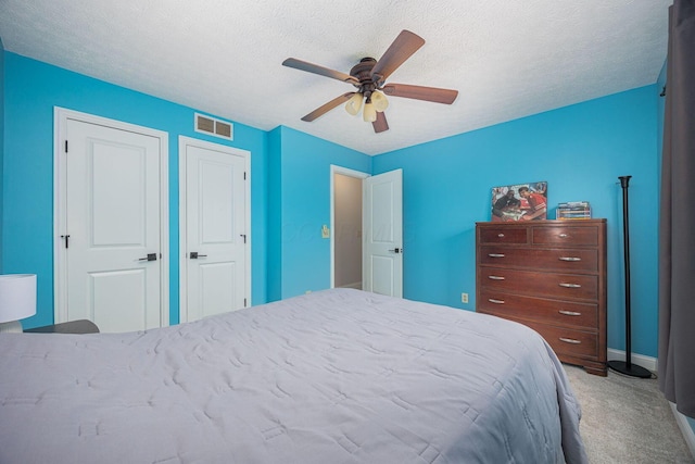 carpeted bedroom with ceiling fan and a textured ceiling