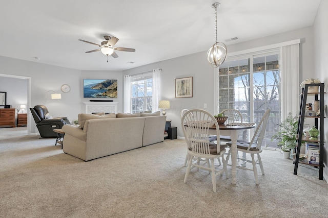 carpeted dining space with ceiling fan with notable chandelier