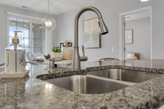 kitchen featuring pendant lighting, stone countertops, a notable chandelier, and sink