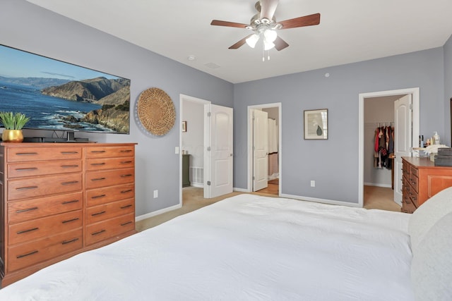 carpeted bedroom featuring a walk in closet, ensuite bathroom, a closet, and ceiling fan