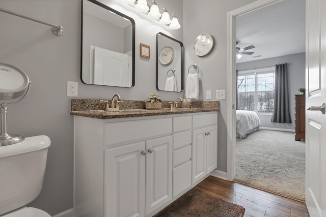 bathroom with wood-type flooring, vanity, toilet, and ceiling fan