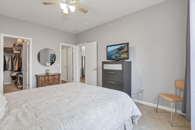 bedroom with ceiling fan, a walk in closet, light carpet, and a closet