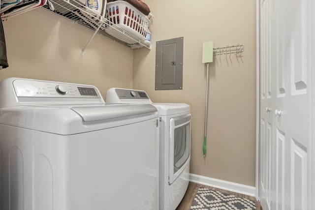 washroom featuring hardwood / wood-style floors, washing machine and dryer, and electric panel