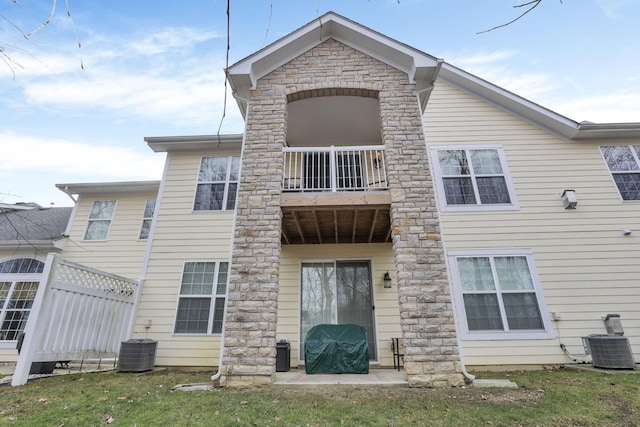 rear view of house featuring central AC unit and a balcony