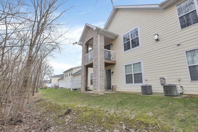 exterior space with a balcony, cooling unit, and a lawn