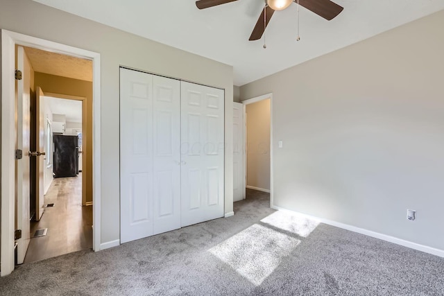 unfurnished bedroom featuring ceiling fan, a closet, and light carpet