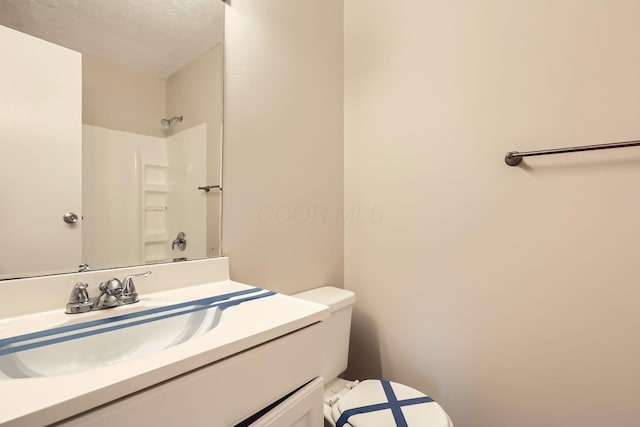 bathroom with vanity, toilet, a textured ceiling, and walk in shower