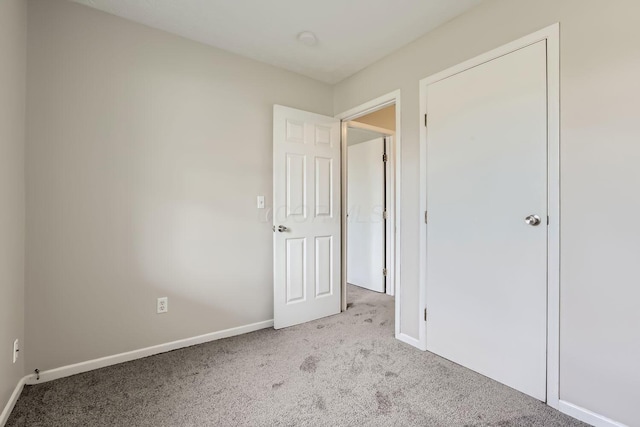 unfurnished bedroom featuring light carpet and a closet