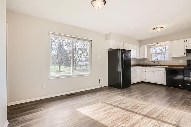 kitchen featuring sink, white cabinets, black appliances, and plenty of natural light