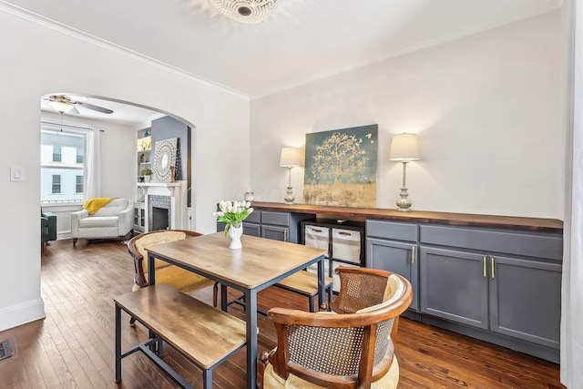 dining space with crown molding, dark wood-type flooring, and ceiling fan