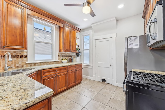 kitchen with sink, light stone counters, tasteful backsplash, light tile patterned floors, and stainless steel appliances