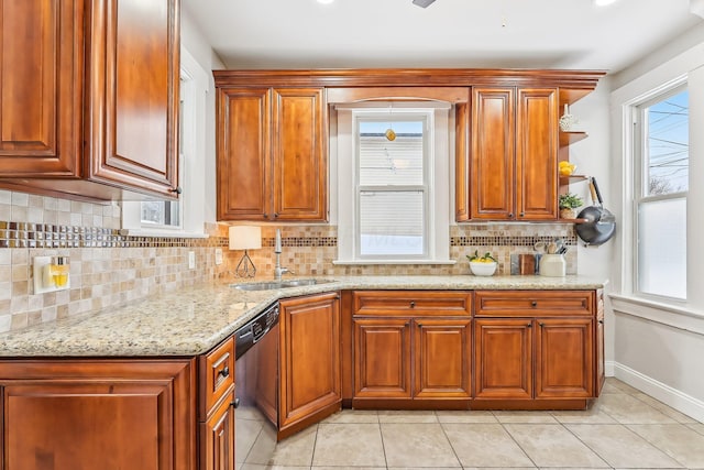 kitchen with sink, light stone counters, light tile patterned floors, stainless steel dishwasher, and decorative backsplash