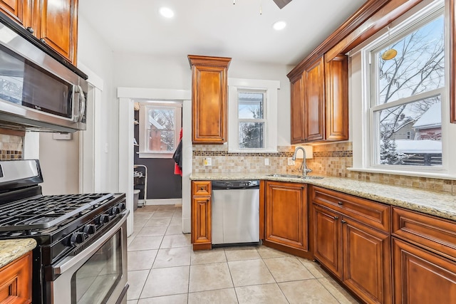 kitchen with stainless steel appliances, tasteful backsplash, light stone countertops, and sink