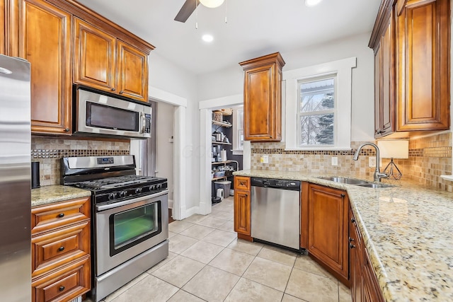 kitchen with sink, stainless steel appliances, light stone countertops, light tile patterned flooring, and decorative backsplash