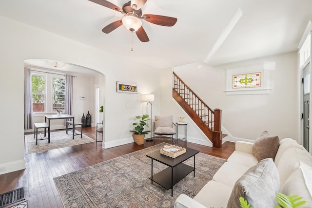 living room featuring visible vents, arched walkways, stairs, and dark wood-style flooring