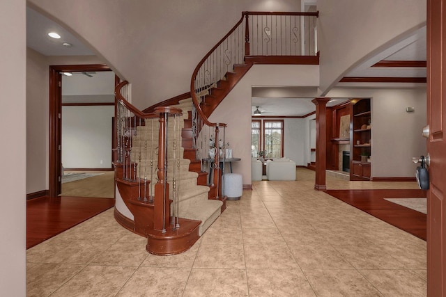 stairway featuring french doors, tile patterned floors, crown molding, ceiling fan, and ornate columns