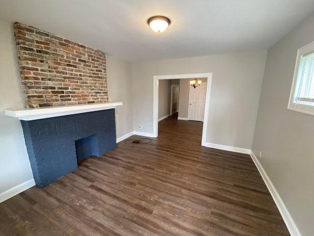 unfurnished living room featuring dark hardwood / wood-style floors and an inviting chandelier