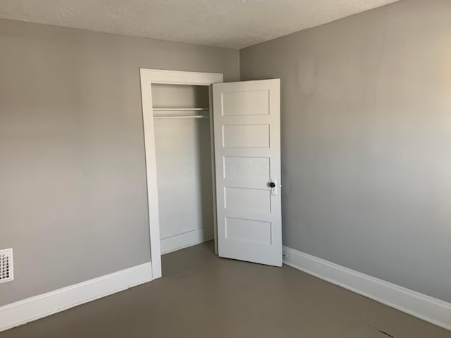 unfurnished bedroom featuring a textured ceiling and a closet