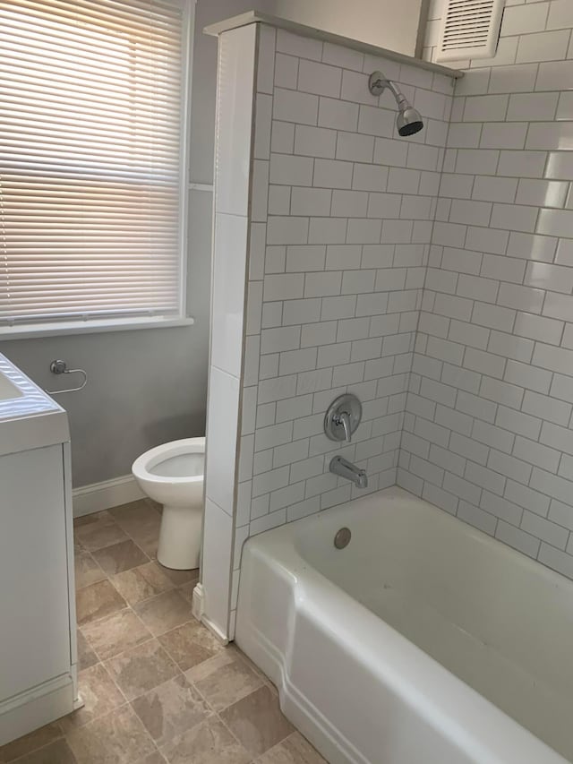 full bathroom featuring vanity, washer / dryer, tiled shower / bath combo, and toilet