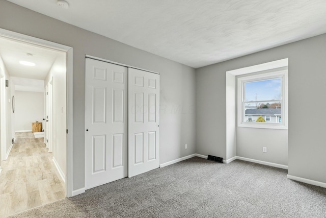 unfurnished bedroom with light colored carpet and a closet