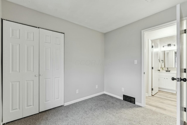 unfurnished bedroom with light colored carpet, sink, connected bathroom, and a closet