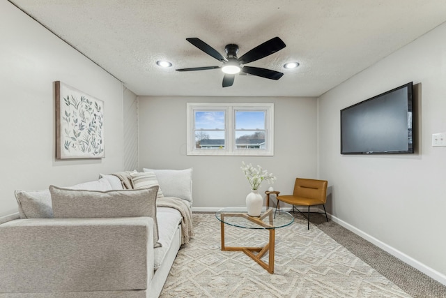 carpeted living room with ceiling fan and a textured ceiling