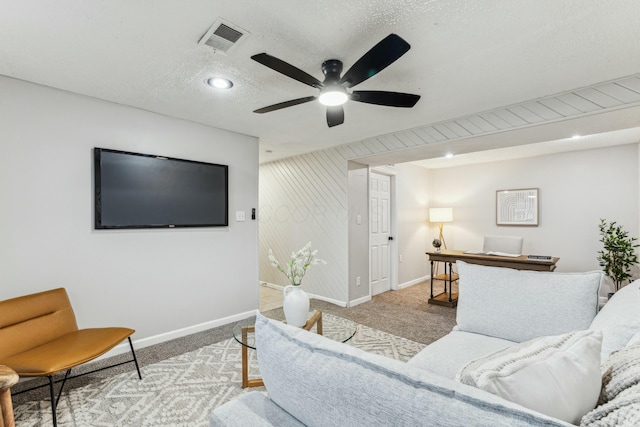 living room with a textured ceiling, light colored carpet, and ceiling fan