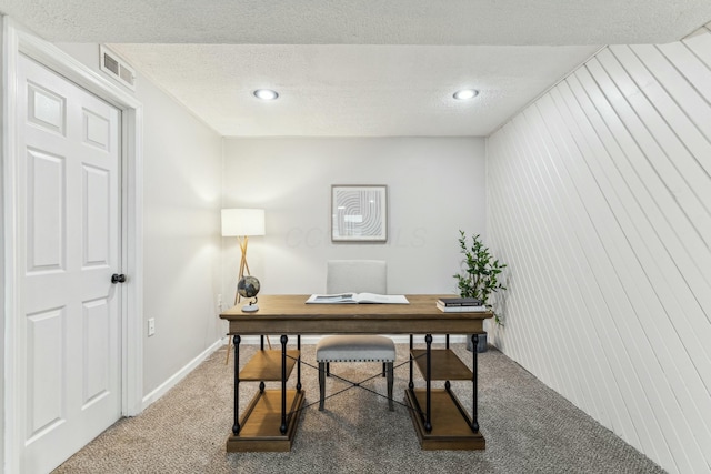 carpeted home office featuring a textured ceiling and wood walls