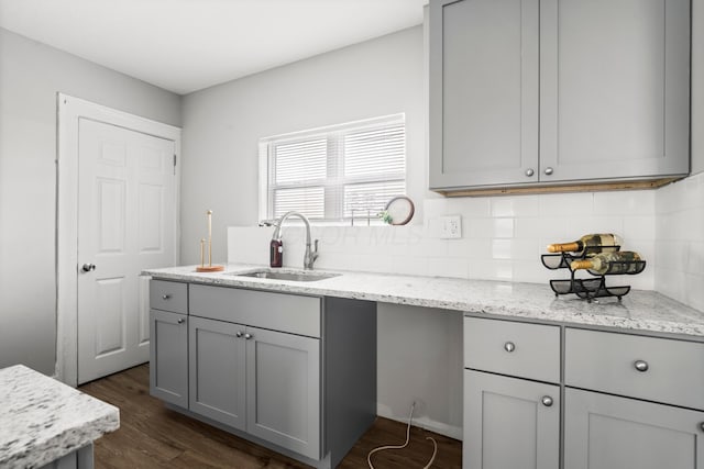 kitchen featuring gray cabinetry, sink, tasteful backsplash, light stone counters, and dark hardwood / wood-style floors