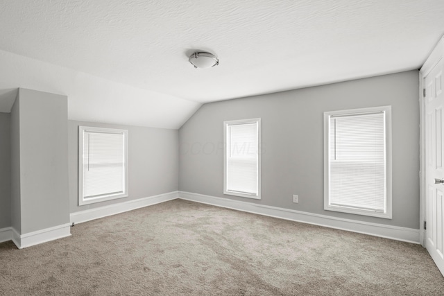 bonus room featuring carpet flooring, plenty of natural light, a textured ceiling, and vaulted ceiling