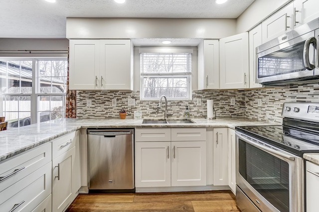 kitchen featuring backsplash, stainless steel appliances, white cabinetry, and sink