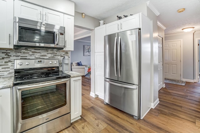 kitchen featuring light stone countertops, tasteful backsplash, a textured ceiling, white cabinets, and appliances with stainless steel finishes